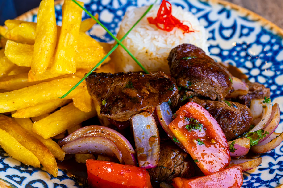En tallerken peruviansk lomo saltado med oksekød, løg, tomat, fritter og ris, repræsentativ for criollo-madlavning
